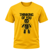 A yellow short-sleeve crewneck t-shirt featuring a black graphic of a stitched voodoo doll with pins and the text 'THINKING OF YOU' printed above it, shown against a plain white background.