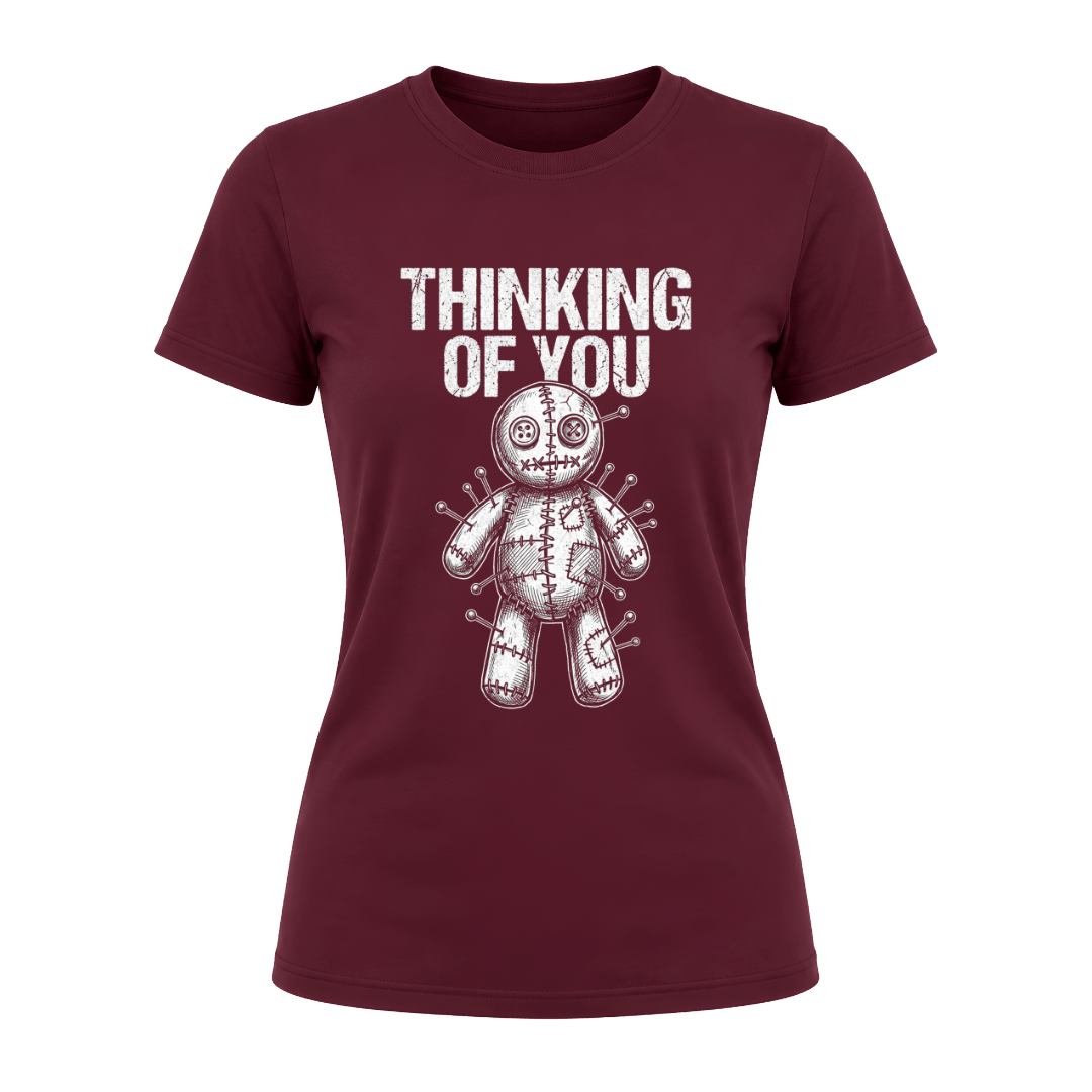 Maroon women’s dark humor graphic tee featuring Thinking of You wording above a pinned voodoo doll illustration