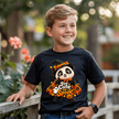 Boy wearing a black kids Halloween T shirt with cute panda witch graphic and Too Cute to Spook pumpkin design