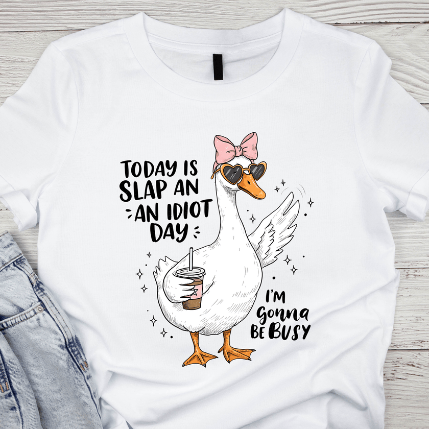 White unisex T-shirt with a cartoon duck wearing sunglasses and a pink bow holding an iced coffee