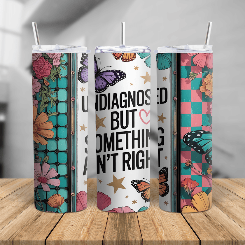 Skinny tumbler with “Undiagnosed But Something Ain’t Right” quote, colorful butterflies, florals, and seamless cup design.