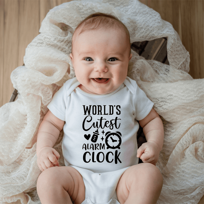 Smiling baby wearing funny World’s Cutest Alarm Clock infant bodysuit in soft white cotton fabric