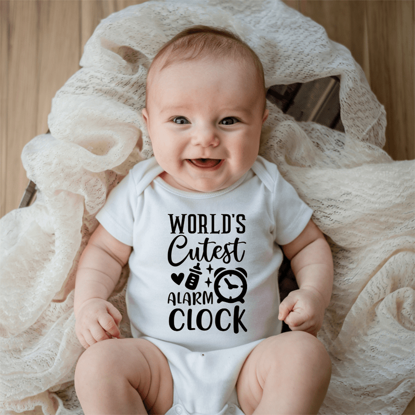 Smiling baby wearing funny World’s Cutest Alarm Clock infant bodysuit in soft white cotton fabric