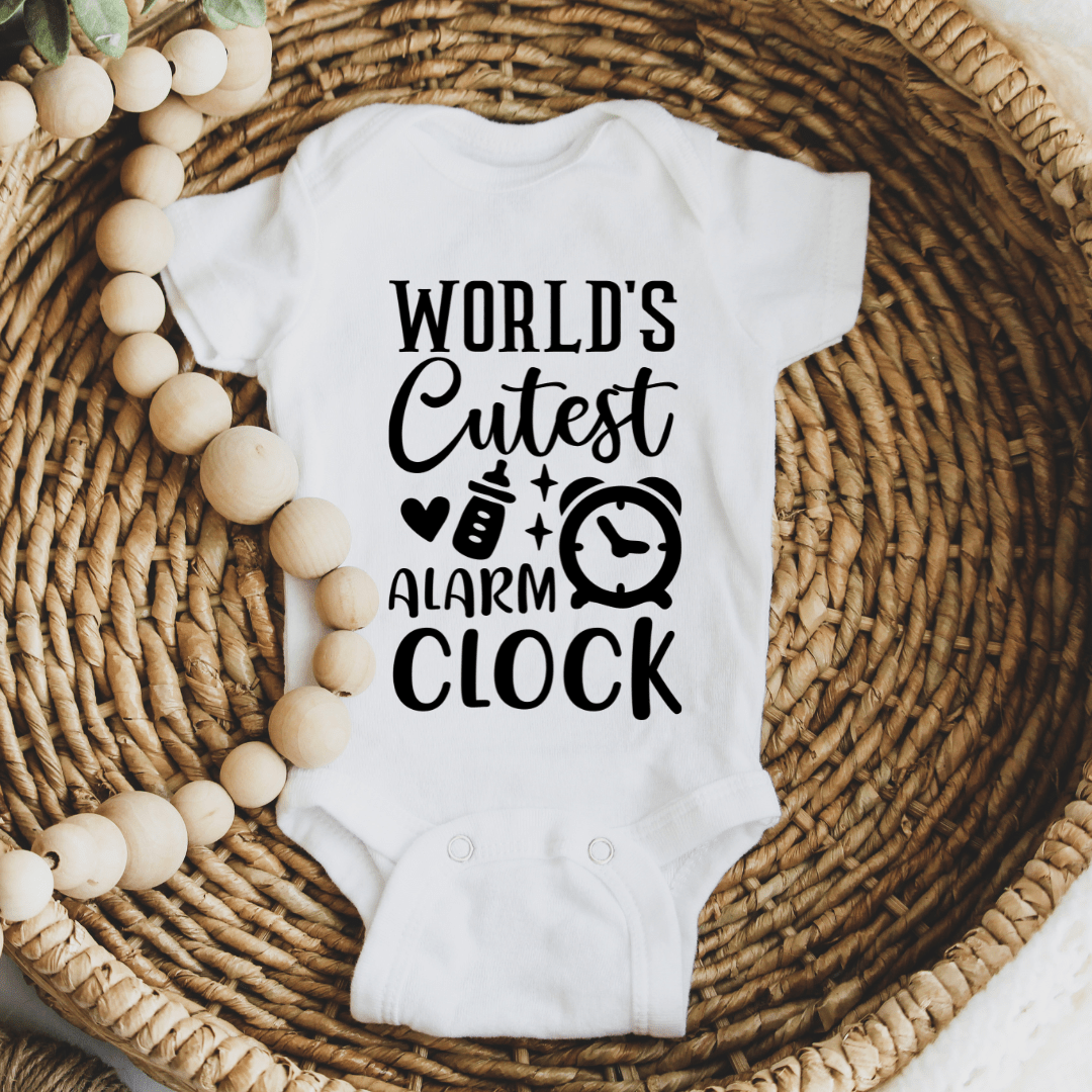 Cozy newborn bodysuit displayed in woven basket with World’s Cutest Alarm Clock black typography print