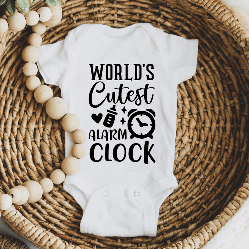 Cozy newborn bodysuit displayed in woven basket with World’s Cutest Alarm Clock black typography print