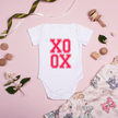 Front view of infant onesie showing centered pink XO XO text