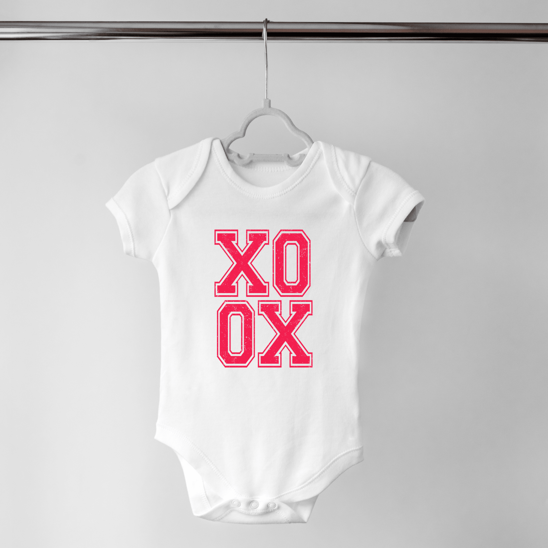 White baby onesie with XO XO print displayed flat on hanger