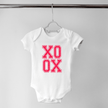 White baby onesie with XO XO print displayed flat on hanger