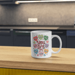 Mug displayed on kitchen counter with cozy sweater sleeve holding it, showcasing full-wrap positive affirmation artwork