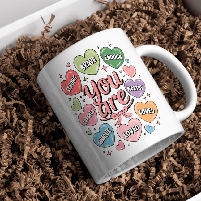White ceramic mug featuring pastel candy hearts with affirmations 