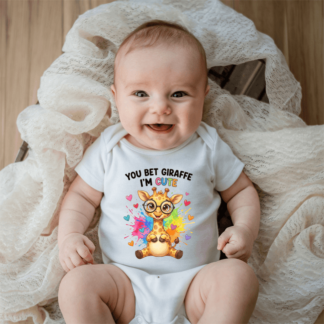Smiling baby wearing white You Bet Giraffe I’m Cute baby onesie with colourful giraffe and heart design