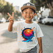 Young boy wearing a white youth basketball T shirt with vibrant orange and blue basketball splash artwork.