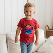 Toddler boy wearing a red youth basketball T shirt featuring colourful splash style basketball artwork.